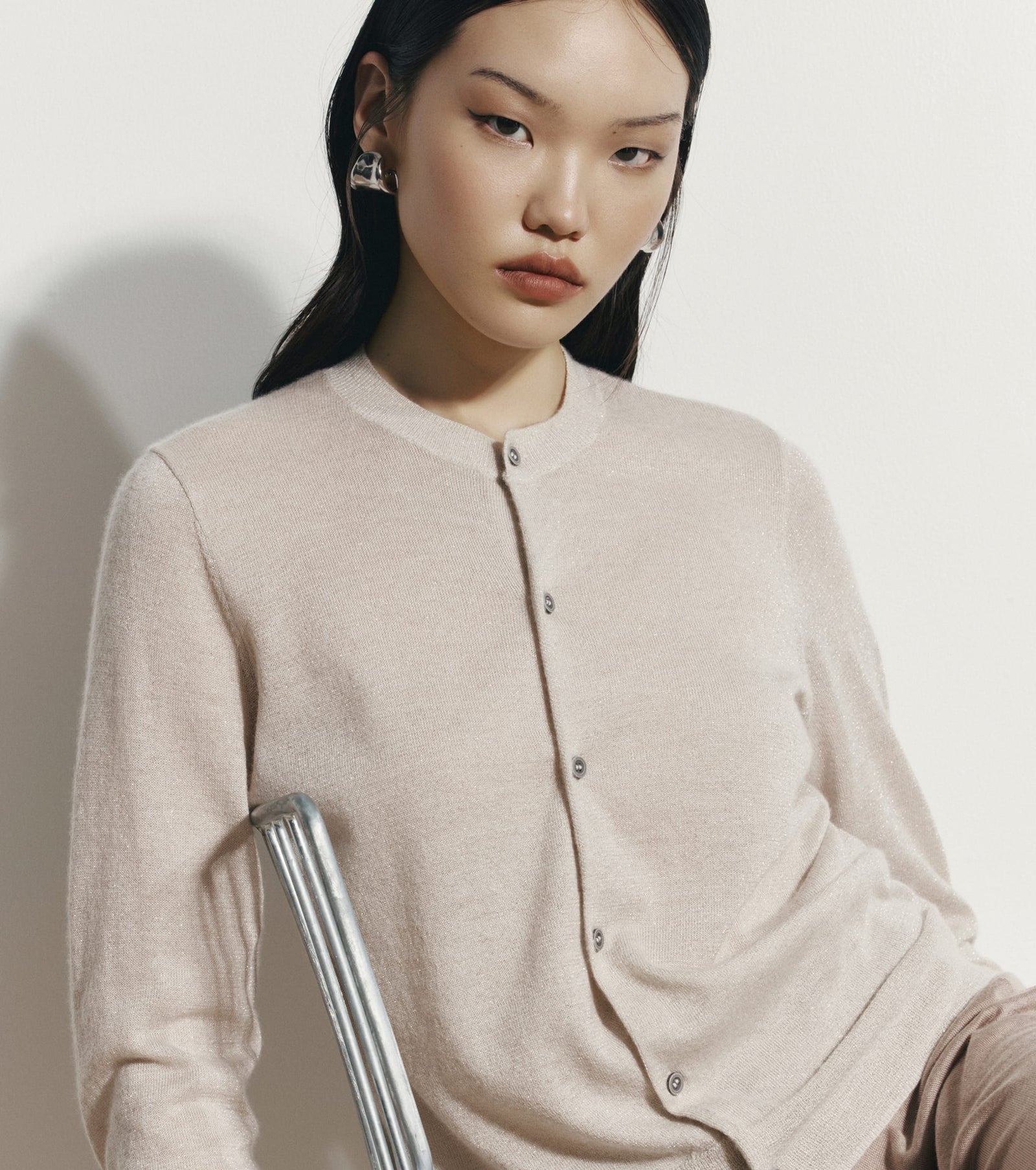 Woman wearing a beige cardigan against a plain background
